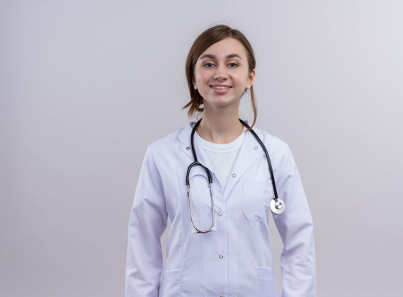 长袍带着微笑的年轻女医生穿着医用长袍和听诊器站在隔离的白色墙壁上 还有复印空间年轻听诊器微笑