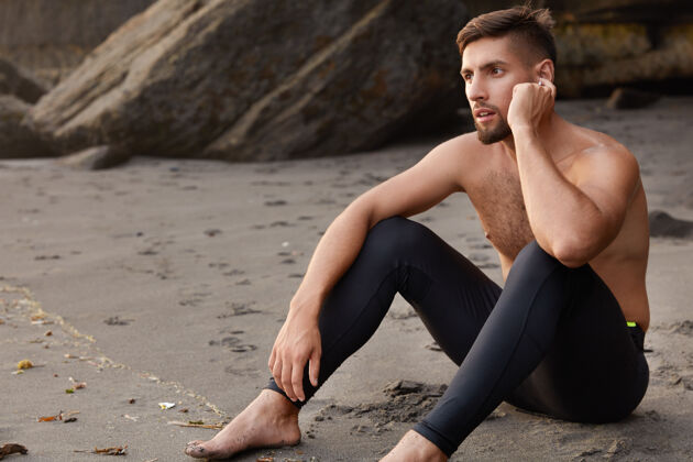 训练严肃的未刮胡子运动员坐在沙滩上的侧身镜头运动服音频裸露