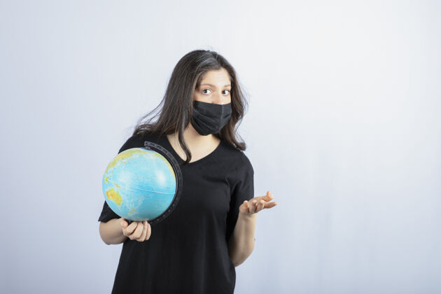 世界戴着医用面具的黑发女人拿着世界地球仪姿势地球女孩