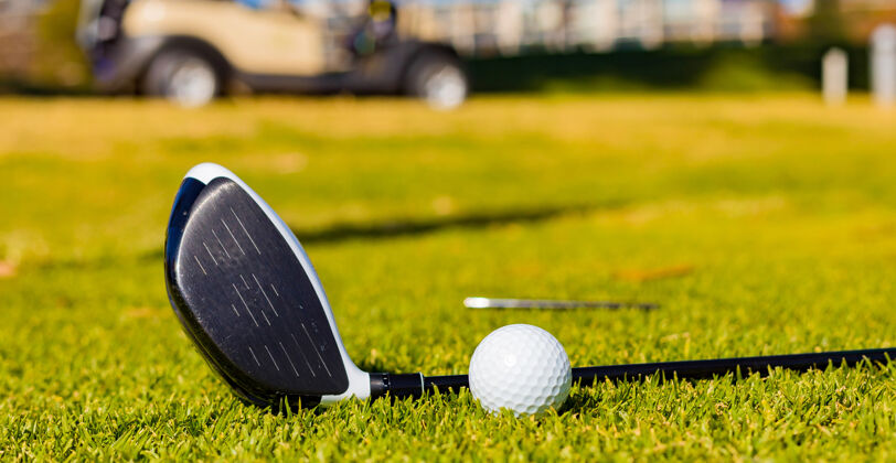阳光高尔夫球杆和草地上的球的浅焦点高尔夫游戏运动
