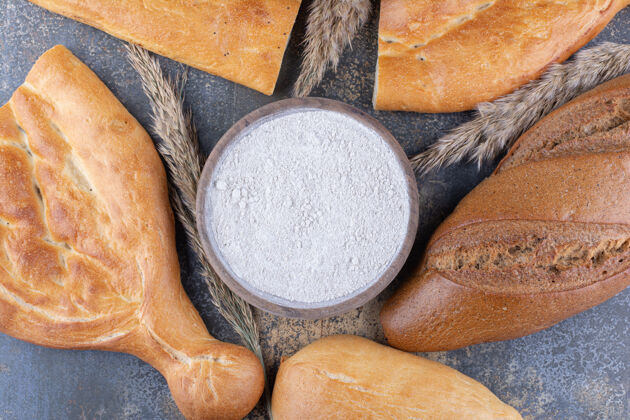 包面包和麦秆围绕在大理石表面的一碗面粉上小麦指挥棒面粉
