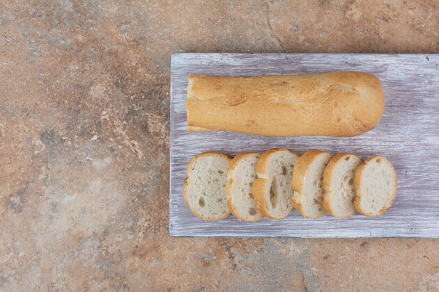 一半把面包片放在木板上面包皮新鲜法式面包