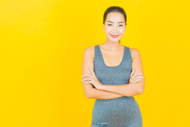 欢呼在黄色的墙上 描绘一位穿着运动服准备锻炼的美丽亚洲年轻女子穿着日本人训练