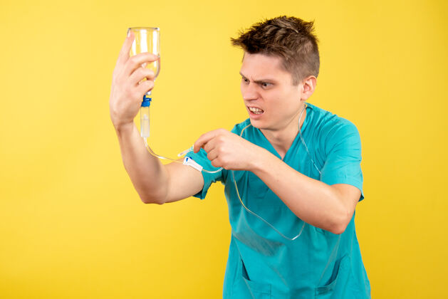 成人正面图身穿医疗服的年轻男医生拿着黄色背景上的滴管滴管男性医学