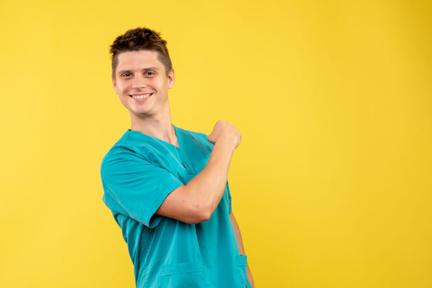 微笑正面图黄色背景上穿着医疗服的年轻男医生肖像医学医学