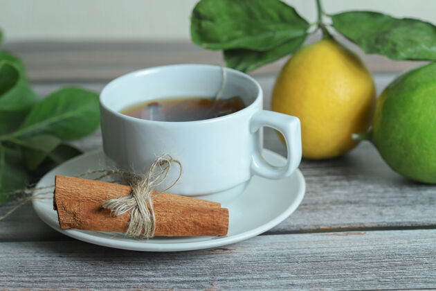 茶一杯加肉桂条和柠檬的茶 放在木头表面水果柑橘叶子