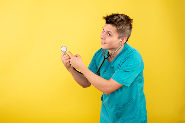 健康正面图黄色桌子上穿着医疗服 带听诊器的年轻男医生成人年轻男性医生医疗