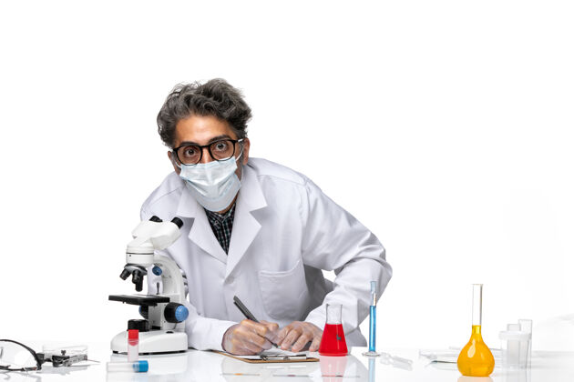 工作前视图中年科学家穿着特殊的白色西装使用显微镜外套人特殊