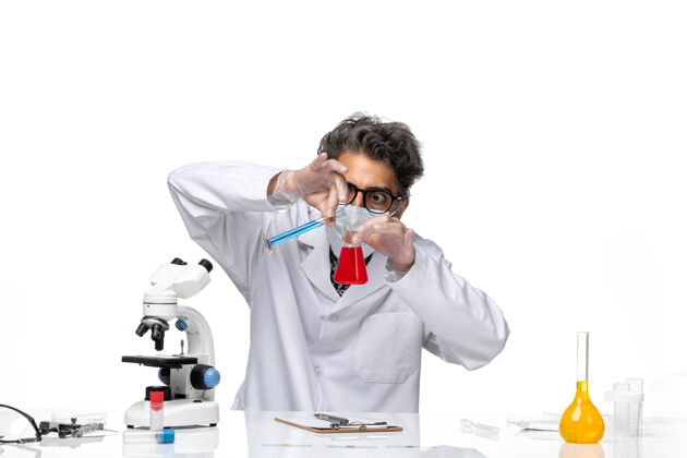 持有正面图穿着特殊套装的中年科学家坐着拿着装有解决方案的烧瓶微笑化学观点