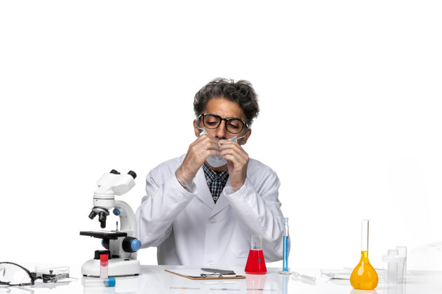 人正面图穿着特殊白色西装的中年科学家围坐在桌子旁 拿着解决方案人桌子专业