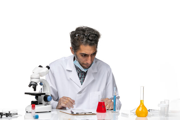 桌子前视图穿着白色医疗服的中年科学家围坐在桌子旁 拿着解决方案实验室化学解决方案