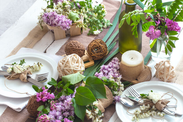 盘子美丽优雅的装饰表 为节日与春天的鲜花和绿色-婚礼或情人节与现代餐具 蝴蝶结 玻璃 蜡烛和礼物 水平 特写 色调餐厅安排菜单