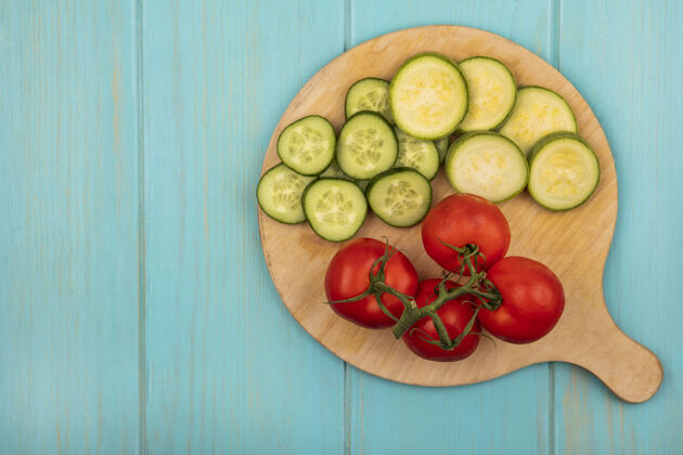厨房新鲜和健康的蔬菜 如西红柿切碎黄瓜和西葫芦在一个蓝色的木墙上复制空间木制厨房板顶视图农业木材西葫芦