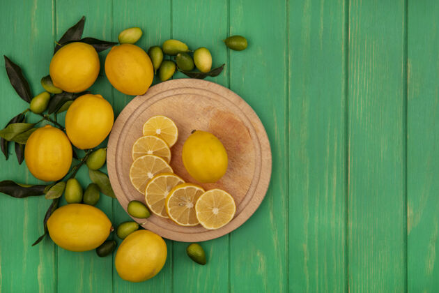 顶部新鲜柠檬切片的顶视图在一个木制的厨房板上 金盏花和柠檬被隔离在一个绿色的木制墙壁上 有复制空间木材配料柠檬