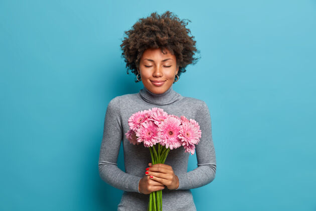 爱快乐浪漫的美国黑人妇女手持美丽的非洲菊花束高领毛衣拥抱休闲