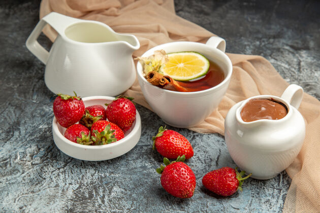 盘子前视图新鲜的红色草莓与茶杯上的深色浅红色浆果茶水果杯子