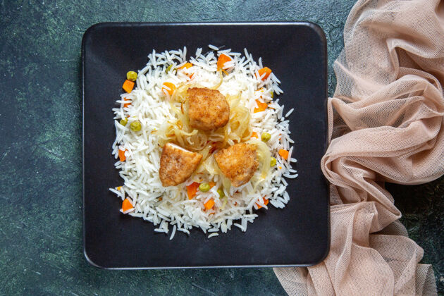 米饭在黑暗的桌子上 盘子里放着美味的煮米饭 里面有豆子和肉食物横盘子