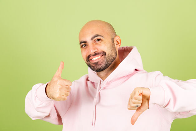 人年轻秃顶的白人男子穿着粉色连帽衫孤立 积极的一个拇指向上一个向下表情向上显示