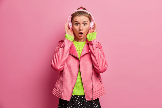 恐惧惊讶的欧洲女人用耳机听好歌 震惊的是音量太大 在播放列表中挑选歌曲 决定听什么 穿着时髦的衣服欧式情绪室内