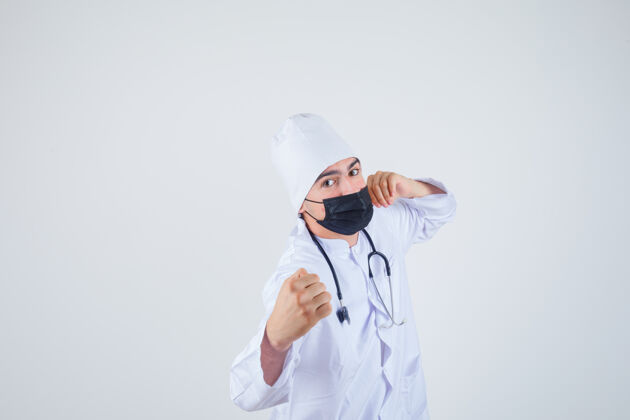 职业身穿白色制服的年轻人 戴着面具 站在战斗的姿势 看起来很自信 正对着前方姿势保健医生