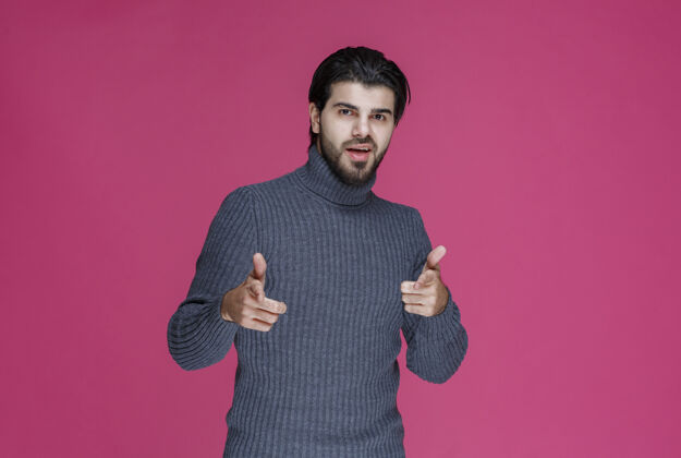 男性穿灰色毛衣的人用手指指着什么东西或介绍某人表演男性年轻