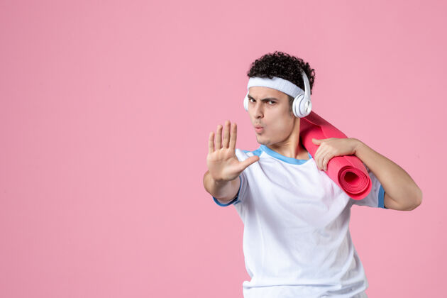 人正面图穿着运动服的年轻男性 粉色墙上有瑜伽垫年轻男性成人肖像