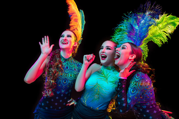 霓虹灯美丽的年轻女子在狂欢节 时尚的化装服装与羽毛的黑色背景在霓虹灯下庆典化妆舞会戏剧