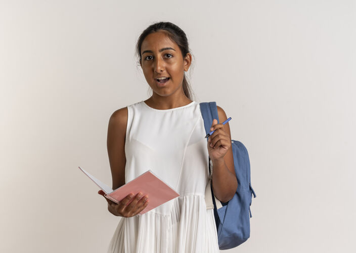 笔记本惊讶的年轻女学生背着包拿着笔记本和笔在白色的女生包背