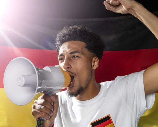 足球欢呼的人拿着德国国旗用扩音器讲话足球杯个人扩音器