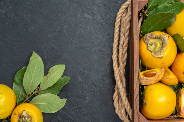 深色顶视图新鲜甜甜的柿子在暗色地板上的盒子里熟透了水果的味道柠檬色黄色盒装