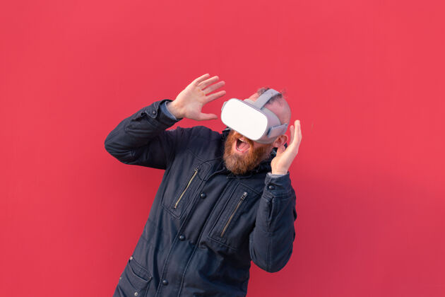 现实在红墙的背景下 一个戴着真人眼镜的男人在街上的情感肖像虚拟现实视觉虚拟