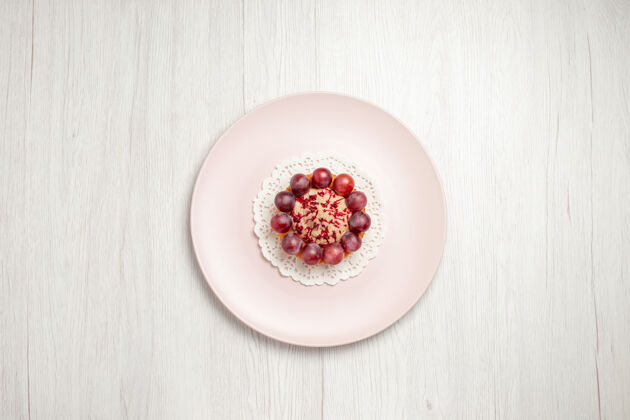 小蛋糕顶视图小蛋糕与葡萄内盘上的白色水果甜点蛋糕美味浆果膳食