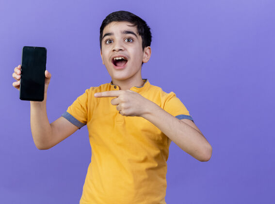 表情给人印象深刻的小男孩指着手机 看着前面孤立的紫色墙壁感觉人男孩