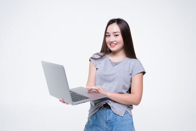 快乐美丽的微笑年轻女子手持笔记本电脑隔离在白色的墙壁上女性女人亚洲