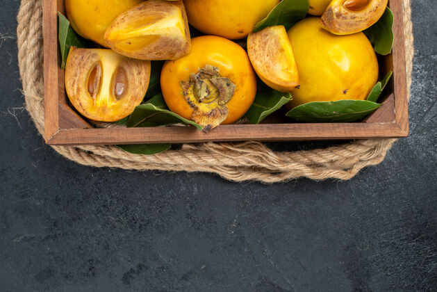 黄色顶视图新鲜甜甜的柿子在盒子里放在深色的桌子上品尝成熟的水果食物顶部成熟