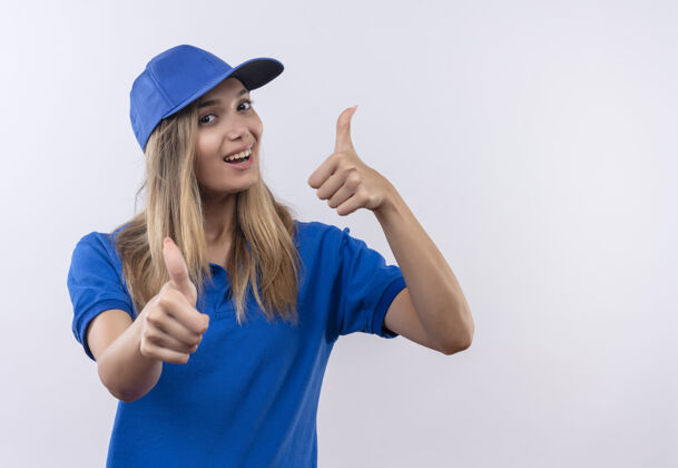 欢乐快乐的年轻送货女孩穿着蓝色制服 戴着大拇指 孤立地站在白色的墙上 留着复印空间送货大拇指年轻