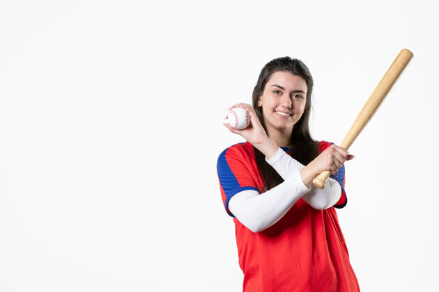 微笑前视图：带球棒和球的女棒球运动员成人年轻支持