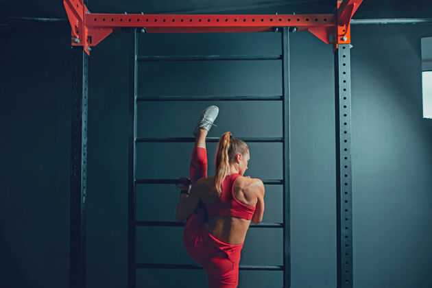 帅气年轻肌肉发达的白种女人在健身房练习运动的女模特做力量练习 训练她的下半身 上半身 伸展运动员健身力量