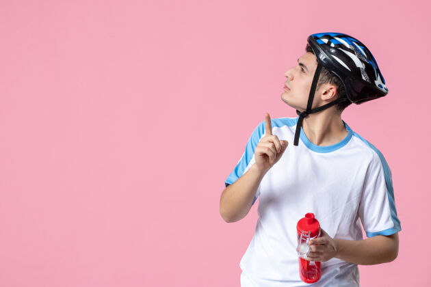 瓶子前视图穿着运动服 戴着头盔 拿着一瓶水的年轻运动员视图成人年轻运动员