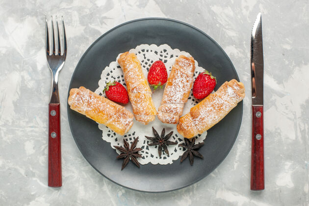 面团糖粉百吉饼的俯视图白色表面上有新鲜草莓的美味面团水果糖早餐