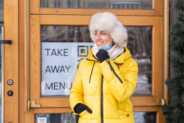 送货在寒冷的冬日 快乐的年轻女子在餐厅门口 刻字 吃外卖工作防护外卖