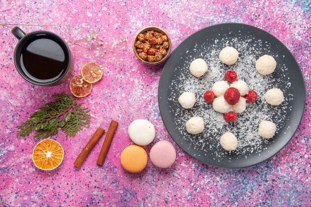 顶视图粉红色书桌上美味的椰子糖甜丸子和法国马卡龙的俯视图球食物糖果