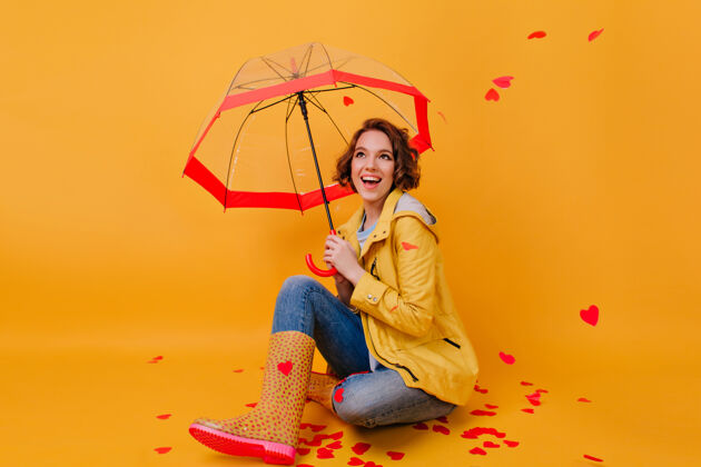 快乐穿着时髦胶鞋的女孩在雨伞下欢笑的室内照片情人节里欣喜若狂的女士鬼混的摄影棚照片微笑成人魅力