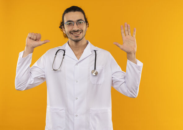 不同微笑的年轻医生 戴着医用眼镜 穿着医用长袍 带着听诊器 在黄色屏幕上显示出不同的手势黄色医学空间