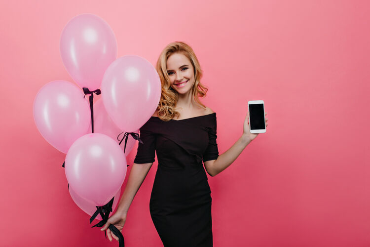电话灵感来源于一位白色女士 波浪式发型 展示新款智能手机积极的高加索女士手持一束派对粉色气球 面带微笑冷微笑手机