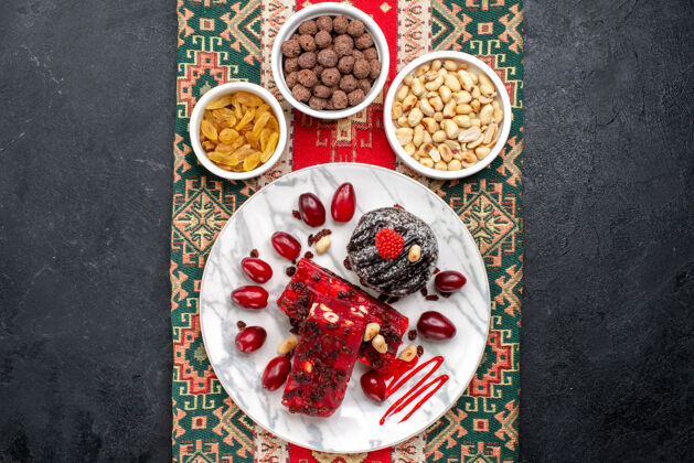 生的顶视图红色山茱萸与坚果和牛轧糖片上的灰色背景糖水果甜坚果晚餐牛轧糖餐厅