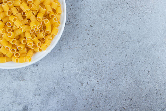 意大利一堆生的移液管把意大利面和鸡蛋和面粉放在一个白色的碗里餐面食黄色