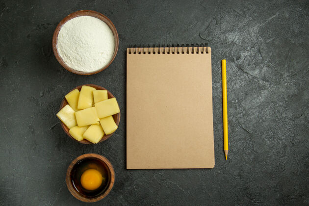 空白顶视图切片奶酪面粉和记事本上的灰色背景面团餐生吃烘烤用餐生的面团