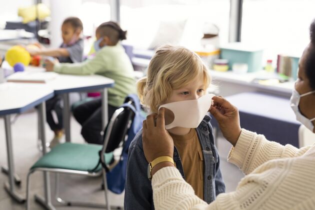 知识女老师帮孩子们戴医用口罩孩子多元文化面具