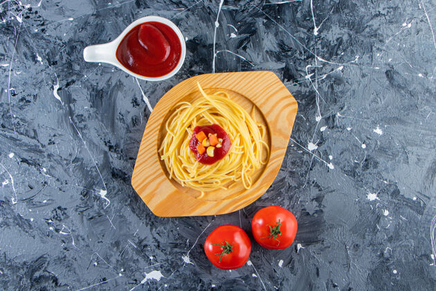 健康美味的意大利面放在木盘上 配上新鲜的西红柿和番茄酱新鲜菜肴番茄